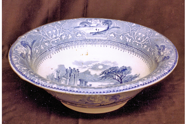 Mid 19thh century glazed ceramic washing bowl manufactured by Thomas Shirley & Co. (the Clyde Pottery Company, Greenock) sometime between 1840 and 1857. Decorated with the 'Saxon' pattern showing 'Saxons' net-fishing lake beside round-towered castle. Border copied from 9th century Saxon pottery combined with lined border and castles in reserves. - 1987.630 - © McLean Museum and Art Gallery, Greenock.