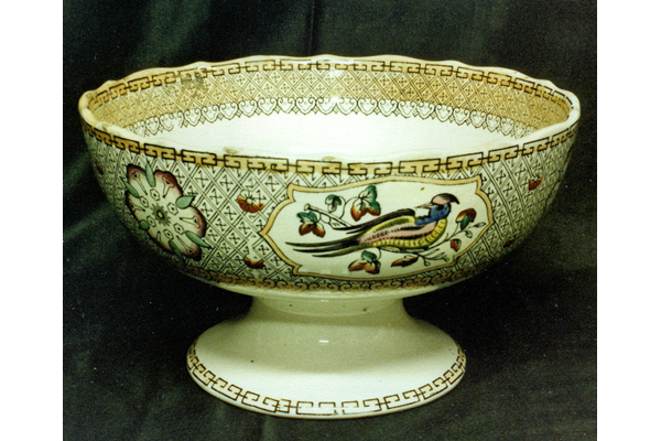 Mid 19th century glazed ceramic punch bowl manufactured by the Clyde Pottery Company, Greenock. Decorated with the 'Cabul' pattern of Tudor roses and tropic birds in reserves, on a border of Persian swastikas with a centrepiece of Chinese furniture & plants. The Cabul pattern seems to have been produced between 1863 and 1875. - 1987.542 - © McLean Museum and Art Gallery, Greenock.