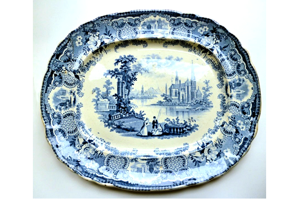Mid 19th century glazed ceramic ashet or serving plate manufactured by Thomas Shirley & Co. (the Clyde Pottery Company, Greenock) sometime between 1840 and 1857. Decorated with the 'Continental Cathedrals' pattern. Purchased with grant-aid from the National Fund for Acquisitions. - 1987.646