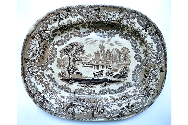 Early 19th century glazed ceramic ashet or serving plate manufactured by the Clyde Pottery Company, Greenock (1814-1841) (James and Andrew Muir). Decorated with the 'British Rivers' pattern in brown. Many British potteries produced 'series' of pictures on their wares. These were usually copied from engravings in late eighteenth or early nineteenth century travel books. - 1987.647