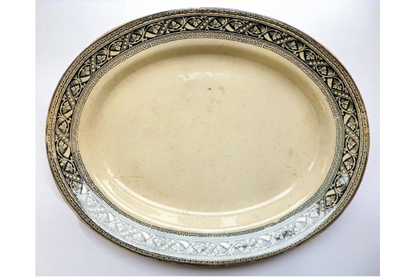 Late 19th century glazed ceramic oval shaped ashet or serving plate manufactured by the Clyde Pottery Company, Greenock between 1862 and 1900. Decorated with the 'Clyde' pattern with a black and polychrome border in classical style. Purchased with grant-aid from the National Fund for Acquisitions. - 1987.673 - © McLean Museum and Art Gallery, Greenock.