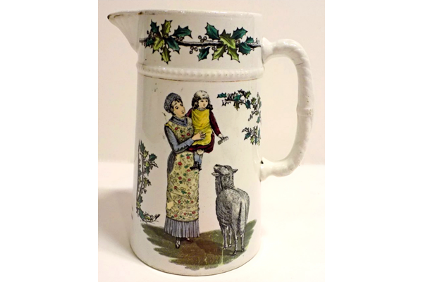 Christmas sauce jug manufactured by the Clyde Pottery Company, Greenock. The jug has a white background decorated with Christmas scenes. Inscribed 'A Joyous Xmas and a Happy New Year' with a mark C.P.Co. - 1980.320 - © McLean Museum and Art Gallery, Greenock.