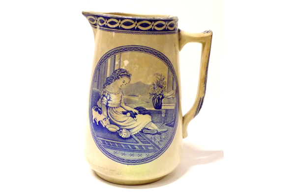 Jug manufactured by the Clyde Pottery Company, Greenock. Decorated with the 'Rose' pattern showing a little girl feeding a cat at a window with distant scene beyond. - 1990.169 - © McLean Museum and Art Gallery, Greenock.