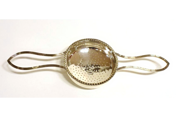Greenock provincial silver juice strainer. George III period, made around 1815. Made by John Heron (fl 1815-1830) of Greenock. The design has a central perforated straining bowl with decorated outer edge. Two handles styled in elongated 'V' shape. - 1980.74