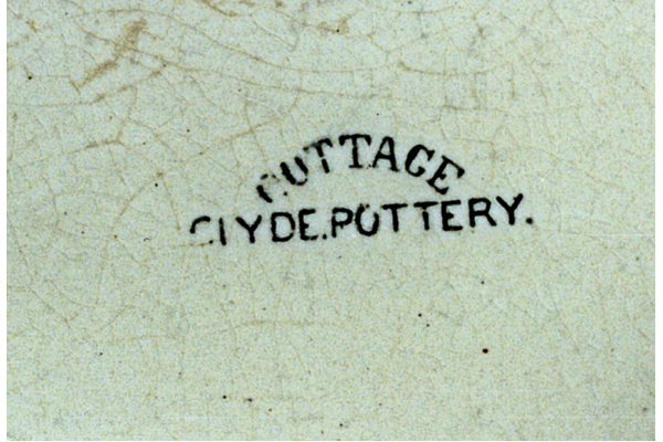 This pattern was used on jugs in the form of round-headed side-reserves with cottage picture; surrounded with spray of Michaelmas daisies; the top border has bishop's mitres & ribbons with daisy-spray mark in capitals. The mark is COTTAGE (curved) over CLYDE POTTERY. © McLean Museum and Art Gallery, Greenock.