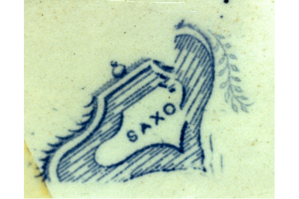 This pattern shows Saxons net-fishing on a lake beside a round-towered castle. Border copied from 9th century Saxon pottery combined with lined border & castles in reserves. Found on jugs, toilet ware and punch-bowls; with various marks including beehive/anchor, sailing yacht; usually printed in grey but also in blue. © McLean Museum and Art Gallery, Greenock.