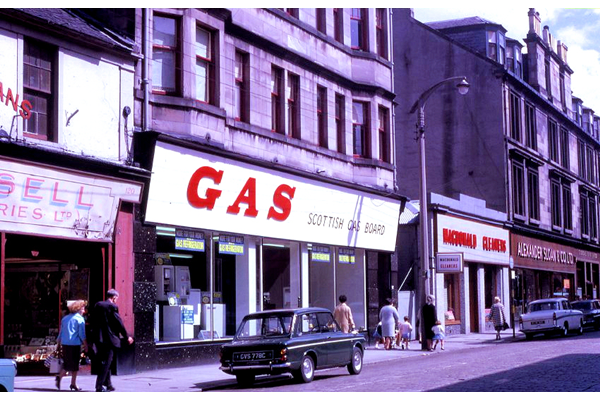 Colour transparency by Eugene Jean Méhat (1920-2000) showing a scene in Greenock during the mid 1960s. This shows a view dated 25-8-67 showing West Blackhall Street with Gas Board showroom, MacDonald Cleaners and Hector Russell shop. - 2008.72.154 - © McLean Museum and Art Gallery, Greenock.
