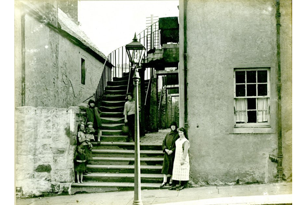 Women and children standing at the entrance to the houses at 19 Balfour Street, Port Glasgow. - 2009.98.35 - © McLean Museum and Art Gallery, Greenock