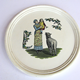 Late 19th century glazed wall plaque decorated with a design of a woman holding a child in her arms and sheep in foreground. Decorative foliage on either side. Made between 1862 and 1900 by the Clyde Pottery Company, Greenock. - 2011.99 - © McLean Museum and Art Gallery, Greenock.