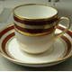 Late 19th century glazed ceramic cup and saucer manufactured by the Clyde Pottery, Greenock. Decorated in white with a decorated band on upper part, two rows of red interspersed with rows of gilding, also gilding above and below red, bottom row is lambrequin border of alternating line and circle.  - L1977.131 - © McLean Museum and Art Gallery, Greenock.