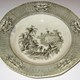 Late 19th century glazed ceramic plate manufactured by the Clyde Pottery Company, Greenock. Decorated with the 'Washington' pattern showing scene across a river gorge with castellated building with flag. Well-dressed figures descend a monumental stair. In the foreground is a summerhouse at the lower left. The border has American eagles in reserves. - 1982.125 - © McLean Museum and Art Gallery, Greenock.