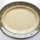 Late 19th century glazed ceramic oval shaped ashet or serving plate manufactured by the Clyde Pottery Company, Greenock between 1862 and 1900. Decorated with the 'Clyde' pattern with a black and polychrome border in classical style. Purchased with grant-aid from the National Fund for Acquisitions. - 1987.673 - © McLean Museum and Art Gallery, Greenock.