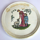 Late nineteenth century Clyde Pottery plaque decorated with a design of a woman standing patting a dog with boy standing next to her. Decorative foliage on either side. Made between 1862 and 1900 by the Clyde Pottery Company, Greenock. - 2011.100 - © McLean Museum and Art Gallery, Greenock.