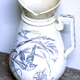 Ewer manufactured by the Clyde Pottery Company Limited, Greenock 1900-1905. Decorated with the 'Waldeck' pattern showing a geometric border with little birds flying through long grass stems and butterflies. - 1987.670 - © McLean Museum and Art Gallery, Greenock.